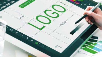 Ein Display mit einer geöffneten App, auf dem ein grüner Schriftzug und Logo zu erkennen sind. Eine Hand hält einen Stift, mit dem sie am Display arbeitet.