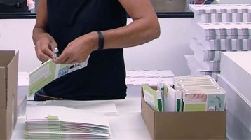 Eine Person packt Werbemittel in einen Karton zusammen